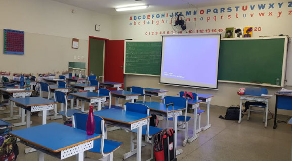 Sala de aula com mesas, cadeiras e recursos pedagógicos